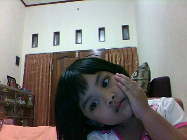 Mira resting her cheek on her hand as a child