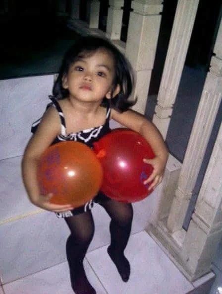 Mira holding balloons as a child